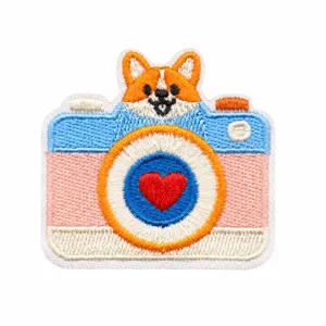 Geborduurde camera-applicatie met corgi en rode hartvormige lens, in detail gefotografeerd