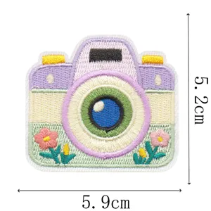 Pastelkleurige geborduurde camerapatch met blauwe lens en bloemen, formaat 5,9 × 5,2 cm