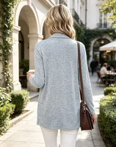Vista da dietro di una donna con cardigan lungo grigio in maglia, pantaloni bianchi e borsa marrone