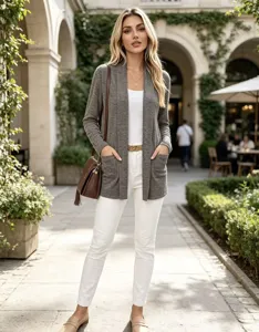 Una donna indossa un cardigan grigio aperto con tasche applicate in un cortile con portici