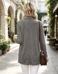 Vista da dietro di una donna con cardigan grigio in maglia e pantaloni bianchi sotto un portico