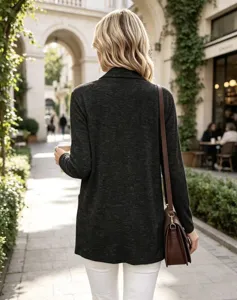 Vista da dietro: donna con cardigan grigio scuro, pantaloni bianchi e borsa a tracolla marrone