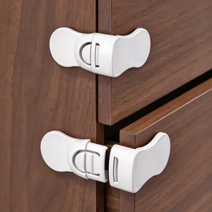 Two white plastic latches fitted across cabinet and drawer gaps against dark wood grain.