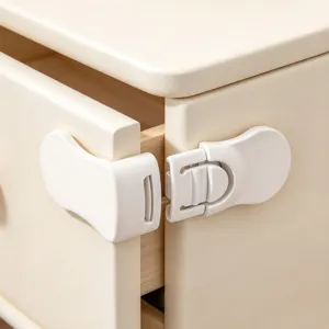 Close-up of a white plastic safety latch fitted between a cabinet drawer and door
