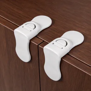 Close-up of two white plastic safety latches fitted along the edge of a dark wood cabinet