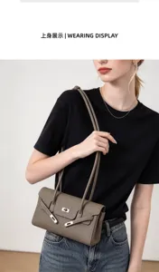Getragene taupefarbene Tasche mit Struktur, Klappe und silbernem Verschluss zu schwarzem Oberteil