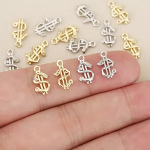 Close-up of gold and silver dollar sign charms with tiny clear stones on a fingertip