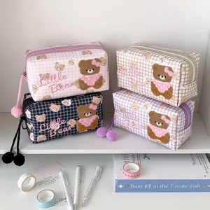 Vier karierte Kosmetiktaschen mit Bärenmotiv in Rosa, Taupe, Schwarz und Lila, mit flauschigen Pompons