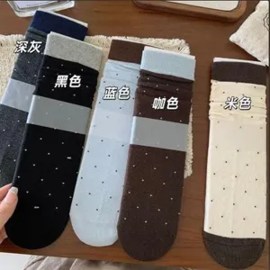 Fünf gepunktete Socken in Grau, Schwarz, Blau, Braun und Creme liegen auf einer Holzfläche