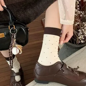 Nahaufnahme cremefarbener mittelhoher Socken mit braunem Bund und Punkten zu Loafern