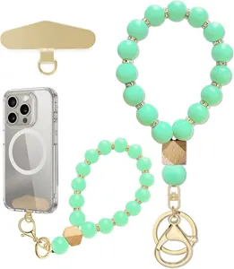 Flat lay of mint-green beaded wrist straps with gold-tone charms and phone tether tab