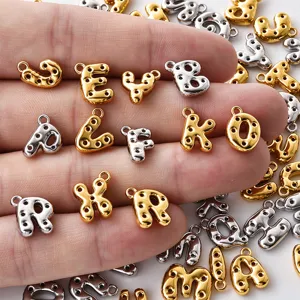 Close-up of gold and silver bubble-style letter charms with perforated details resting on a hand