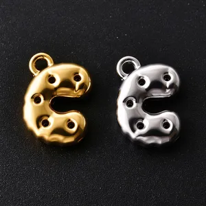Close-up of gold and silver bubble-style letter C charms with loop tops and perforated surfaces
