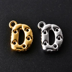 Close-up of two polished D-shaped letter charms in gold and silver, with dotted details and loops