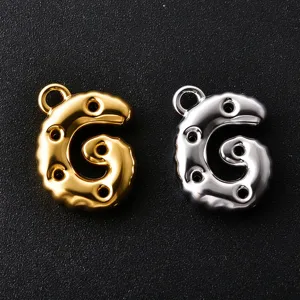 Close-up of gold and silver G-shaped bubble charms with hanging loops and round cutout details