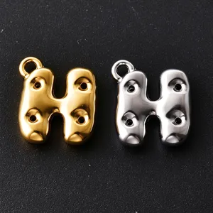 Close-up of bubble-style H letter charms in gold and silver, with raised details and loop rings