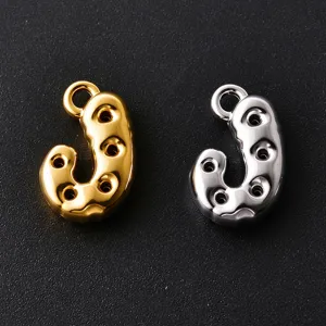 Close-up of polished gold and silver J-shaped charms with hanging loops and round cutouts