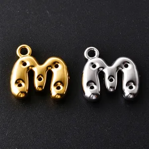 Two glossy balloon-style letter M charms in gold and silver, with hanging loops and small holes