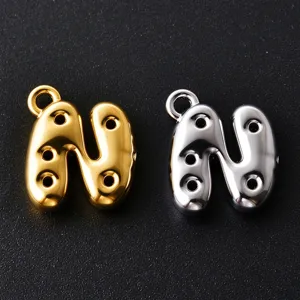 Close-up of gold and silver bubble-style N pendants with loop clasps and three round cutouts