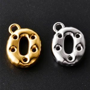 Close-up of polished gold and silver O-shaped letter charms with loop clasps and raised details
