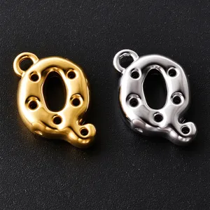 Close-up of two glossy Q-shaped metal charms in gold and silver, with loops and small holes