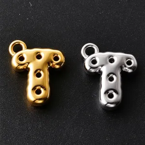 Close-up of polished T-shaped metal charms in gold and silver, with hanging loops and round holes