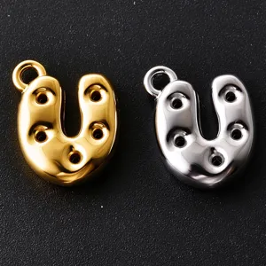 Close-up of two U-shaped metal charms in gold and silver, each with round holes and a loop