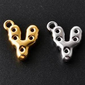 Close-up of glossy gold and silver V-shaped metal charms with round loops and cutout holes