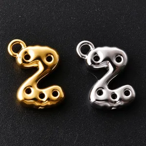 Close-up of glossy bubble-shaped number two charms in gold and silver, each with a round loop
