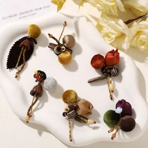 Six handmade fabric-and-bead ornaments arranged on a white tray, with colorful textured details.