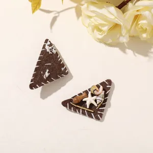 Two brown felt triangles with white stitches, shells, a starfish and small decorative accents