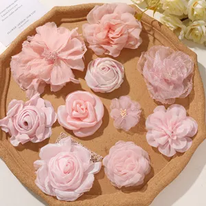 Overhead view of assorted pink fabric roses and layered chiffon flowers arranged on a wooden tray