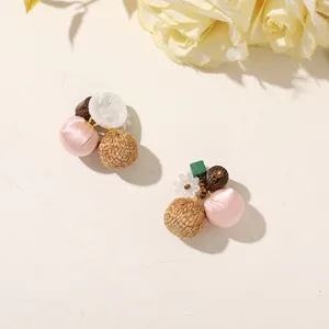 Playful earrings with woven straw balls, pink fabric beads, white flowers and wooden accents