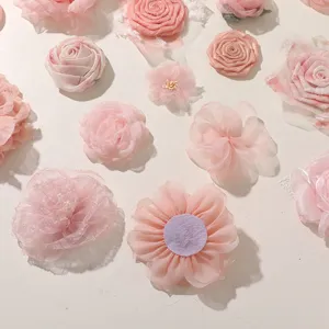 Top-down view of pink fabric roses and daisies arranged on a white surface in soft pastel shades