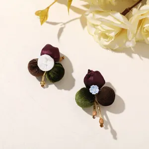 Close-up of velvet fabric balls and satin buds with gold-tone stems and wooden bead accents