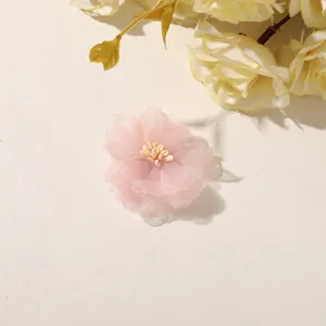 Close-up of a pink sheer fabric flower with a pale yellow center on a light neutral surface