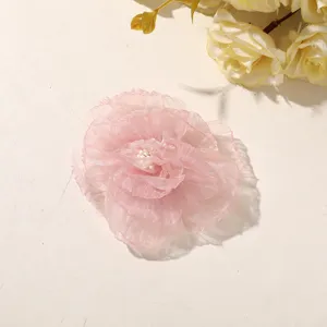 Close-up of layered pink sheer petals with a pearl-like center, laid on a warm white surface