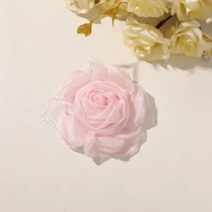 Close-up of layered pink satin petals and white lace backing on a handmade fabric rose