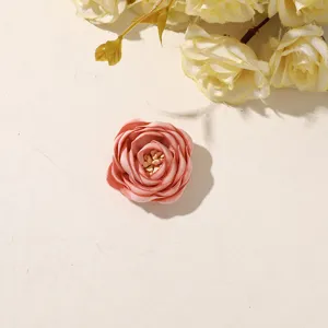 Close-up of a pink satin fabric rose with tiny pale-gold bead accents at its center