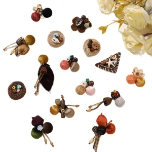 Assorted handmade multicolor textile ball brooches with bead and cord details on a white background