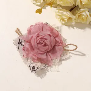 Flat-lay detail of a pink chiffon rose ornament with lace backing and rustic twine accents