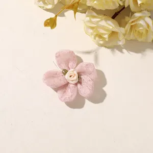 Close-up of a pink mesh fabric flower with a cream satin rose center and small green leaves
