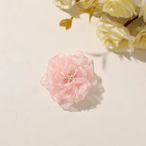 Flat lay of a pink sheer layered flower with an ivory center, beside pale yellow blooms