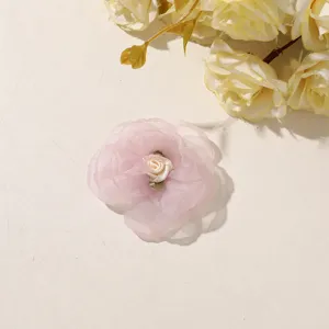 Close-up of a pink sheer tulle flower with an ivory satin rose center on a beige surface