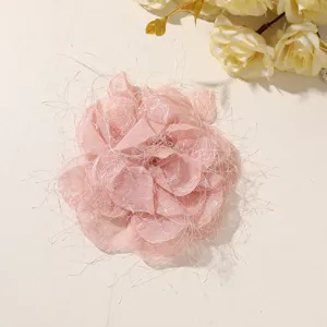 Overhead view of a pink layered mesh flower with shimmering fibers on a light beige background