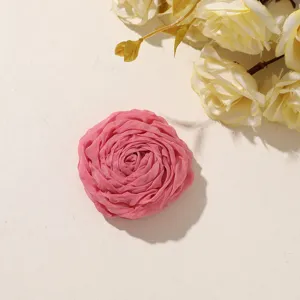 Close-up of a pink layered fabric rose with softly gathered petals against a warm ivory background