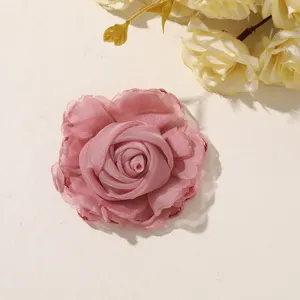 Close-up of a layered pink fabric rose with curled petals, styled on a light neutral background