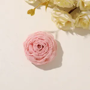 Close-up of a layered pink fabric flower with softly curled petals, arranged on an ivory surface