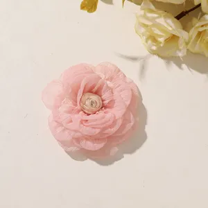 Close-up of a pink fabric flower with layered crinkled petals and a small ivory bud center