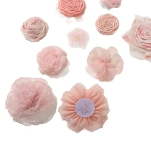 Assorted pink fabric flowers, including roses and chiffon blooms, arranged on white